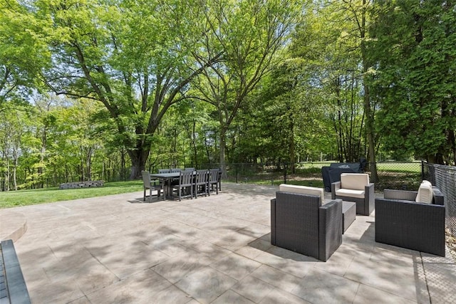 view of patio / terrace with outdoor lounge area, outdoor dining area, fence, and view of scattered trees