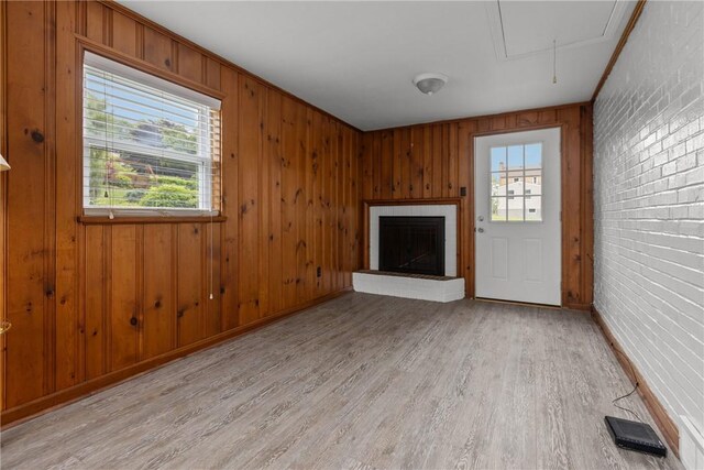 202 Pickwick Dr, Bethel Park, PA 15102 - unfurnished living room with light wood-type flooring, a brick fireplace, plenty of natural light, wood walls, and attic access