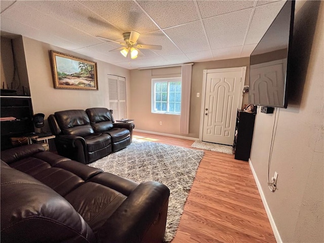 living room featuring a ceiling fan, baseboards, and light wood-style flooring
