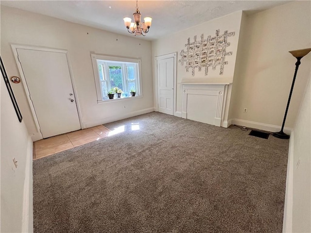 unfurnished living room featuring carpet flooring, a chandelier, and baseboards