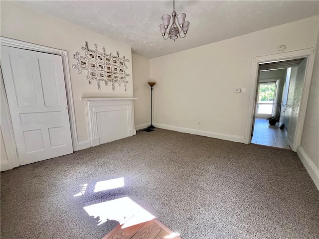 carpeted spare room featuring a chandelier and baseboards