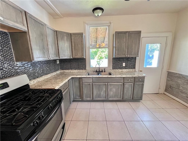 kitchen with stainless steel gas range, a sink, plenty of natural light, and decorative backsplash