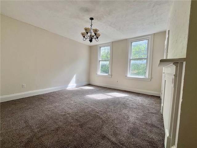 unfurnished living room featuring carpet floors, baseboards, a chandelier, and a textured ceiling