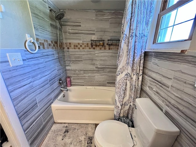 full bathroom with toilet, tile walls, and shower / tub combo with curtain