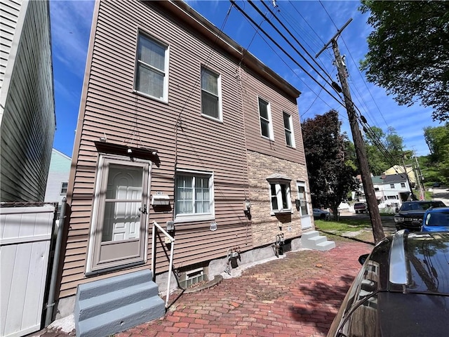 view of side of home with entry steps and fence