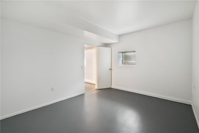 empty room with concrete flooring and baseboards