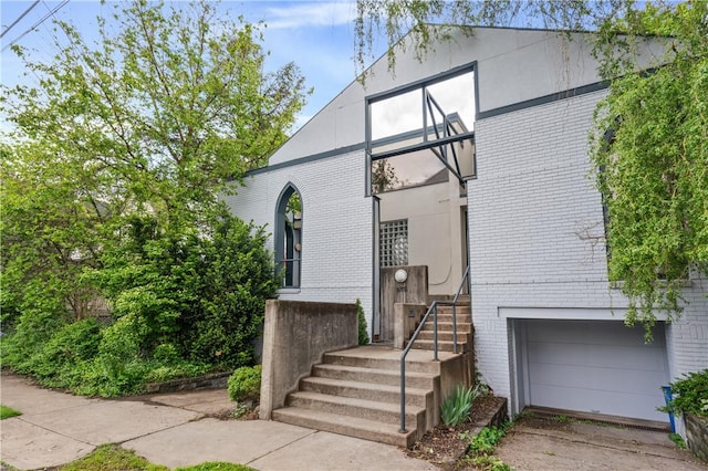 view of front of house with brick siding, an attached garage, and driveway