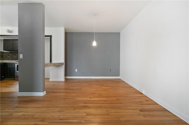 unfurnished dining area featuring light wood-style flooring and baseboards