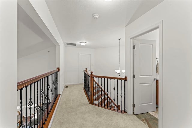 hallway with an upstairs landing, a chandelier, and baseboards