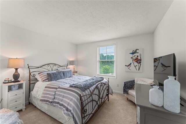 bedroom featuring light carpet, a textured ceiling, and baseboards