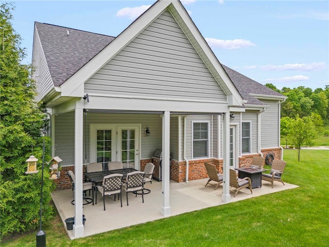 rear view of property with brick siding, a yard, a patio area, and a shingled roof