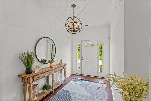 entrance foyer featuring a chandelier, ornamental molding, dark wood-type flooring, and baseboards