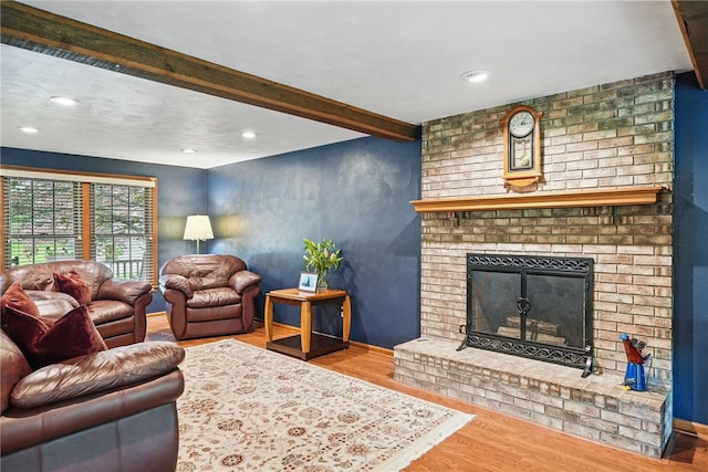 living area with wood finished floors, a brick fireplace, recessed lighting, baseboards, and beamed ceiling