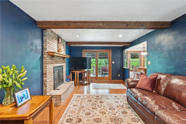 living area featuring beamed ceiling, wood finished floors, a brick fireplace, baseboards, and recessed lighting