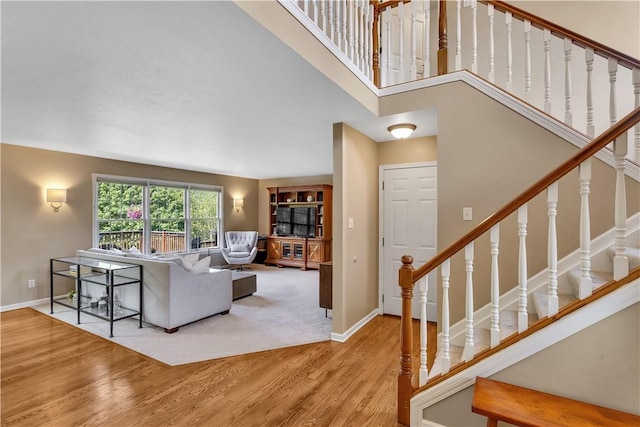 living room featuring wood finished floors, baseboards, stairs, and a high ceiling