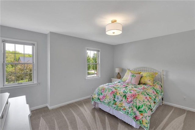 carpeted bedroom featuring multiple windows and baseboards