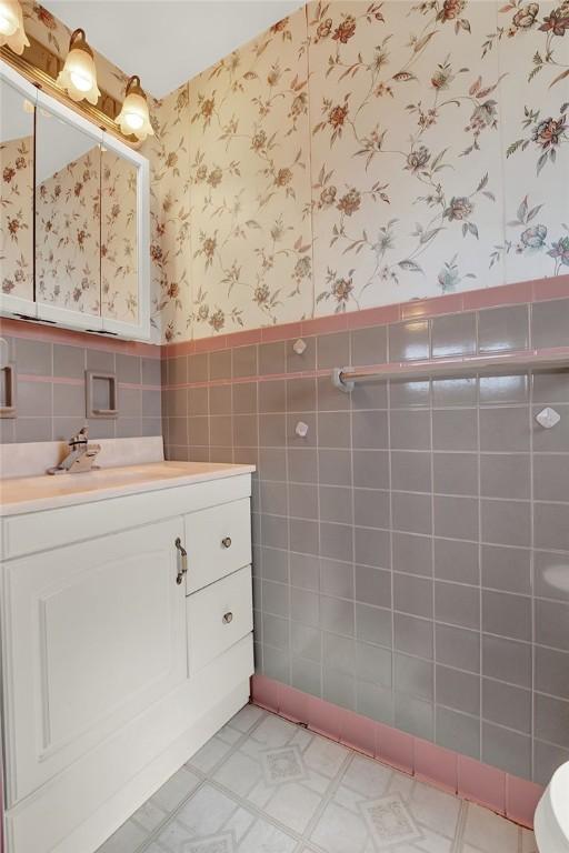 1409 Gill Hall Rd, Jefferson Hills, PA 15025 - bathroom featuring wallpapered walls, tile walls, vanity, a wainscoted wall, and tile patterned floors