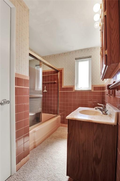 1409 Gill Hall Rd, Jefferson Hills, PA 15025 - full bathroom featuring tile walls, wallpapered walls, vanity, shower / bath combination with glass door, and wainscoting