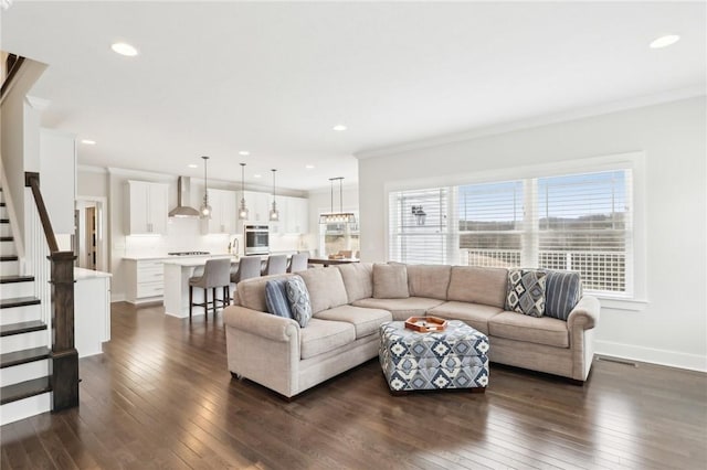 living area featuring ornamental molding, dark wood finished floors, stairs, recessed lighting, and baseboards