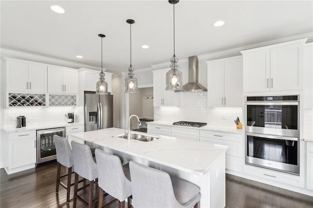 kitchen featuring a sink, wall chimney exhaust hood, stainless steel appliances, beverage cooler, and backsplash