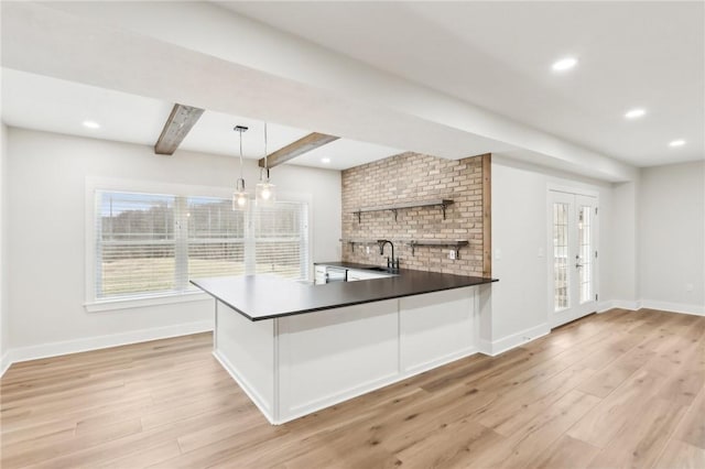 kitchen featuring a sink, open shelves, light wood finished floors, baseboards, and beamed ceiling
