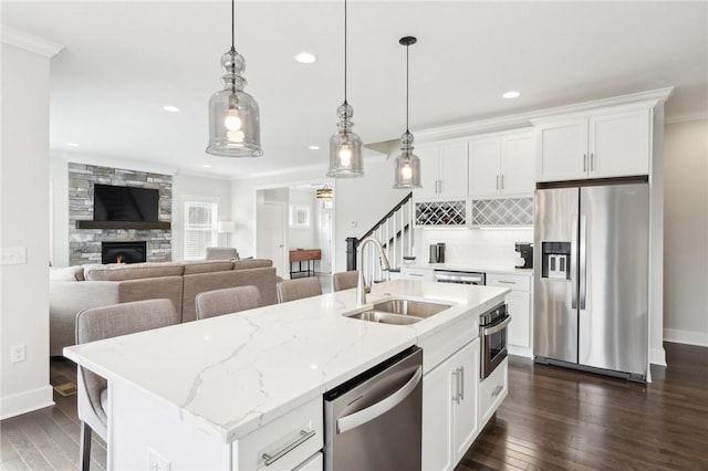 kitchen with stainless steel appliances, a sink, dark wood-style floors, a center island with sink, and recessed lighting