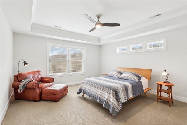 carpeted bedroom with a raised ceiling, baseboards, a ceiling fan, and ornamental molding