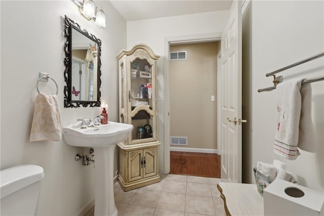 half bath with tile patterned flooring, toilet, and a sink