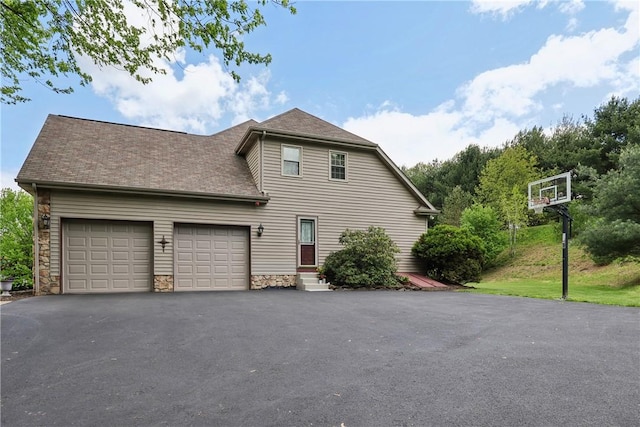 view of front of house featuring asphalt driveway, a garage, stone siding, and roof with shingles