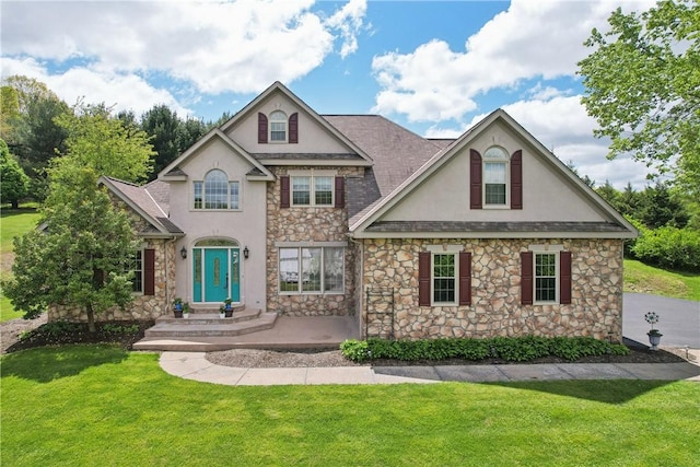 traditional home featuring stucco siding, stone siding, and a front yard