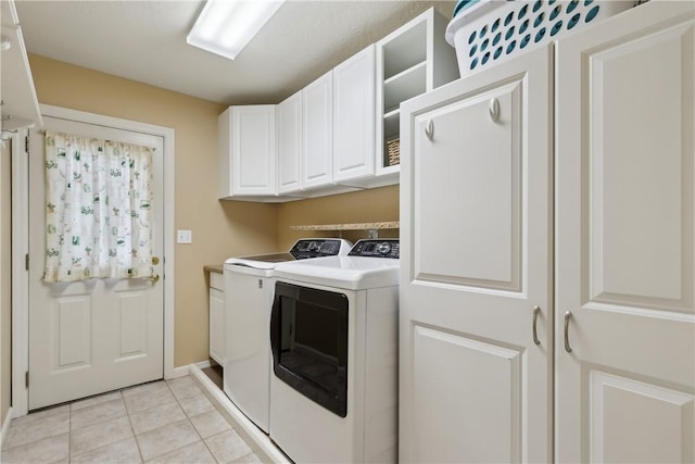 washroom featuring cabinet space, separate washer and dryer, light tile patterned floors, and baseboards