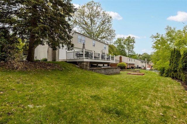 rear view of house featuring a wooden deck and a yard