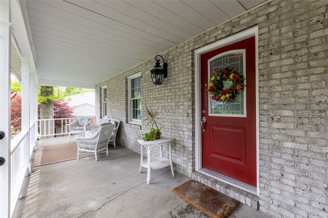 doorway to property featuring a porch and brick siding