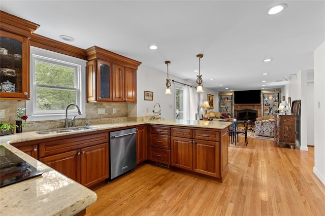 kitchen featuring dishwasher, a sink, a fireplace, light wood-style flooring, and recessed lighting