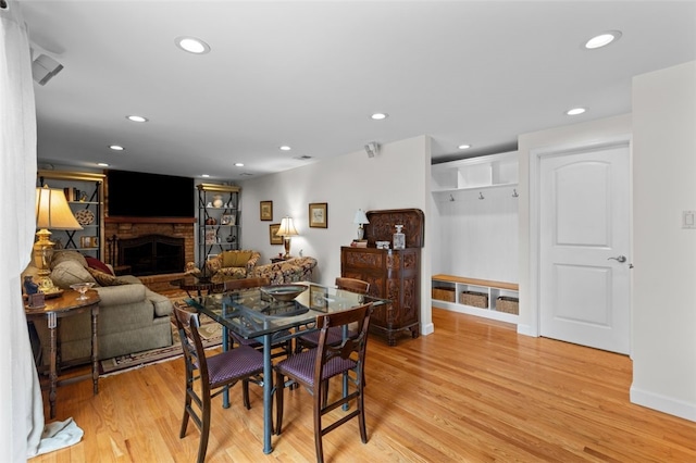 dining area with a brick fireplace, light wood-style flooring, recessed lighting, and baseboards