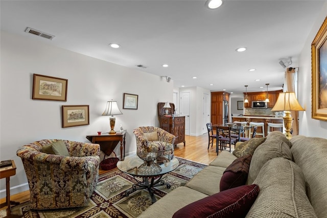living area featuring recessed lighting, light wood-style floors, and baseboards