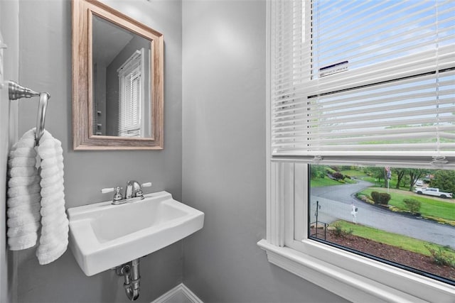 bathroom with healthy amount of natural light, a sink, and baseboards