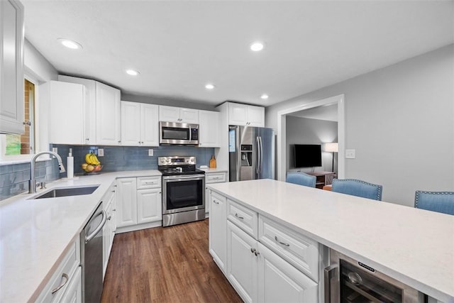 kitchen featuring appliances with stainless steel finishes, a sink, backsplash, dark wood finished floors, and recessed lighting