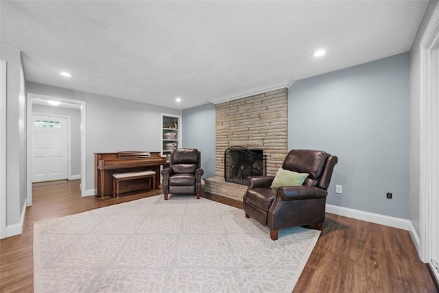 living room with wood finished floors, a fireplace, baseboards, recessed lighting, and a baseboard heating unit