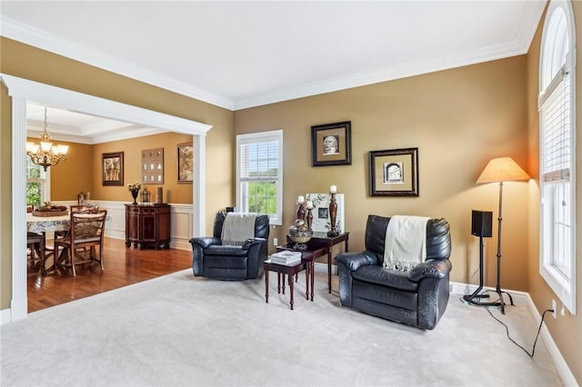 living area featuring a chandelier, carpet, crown molding, baseboards, and wainscoting