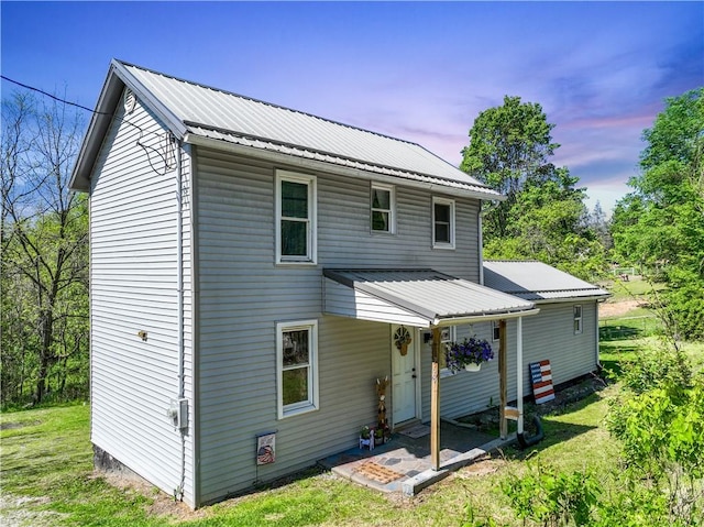 back of property with metal roof and a lawn
