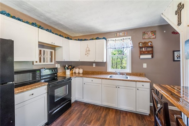 kitchen featuring black appliances, a sink, dark wood-style flooring, white cabinetry, and light countertops