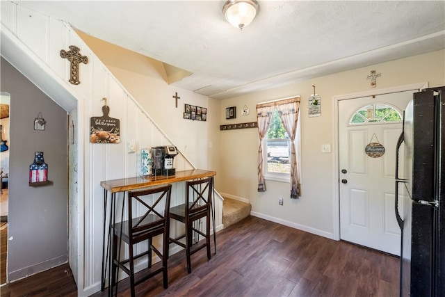 foyer featuring dark wood-style floors, baseboards, and stairway