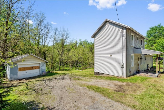 view of home's exterior featuring an outbuilding, a detached garage, a lawn, and a wooded view