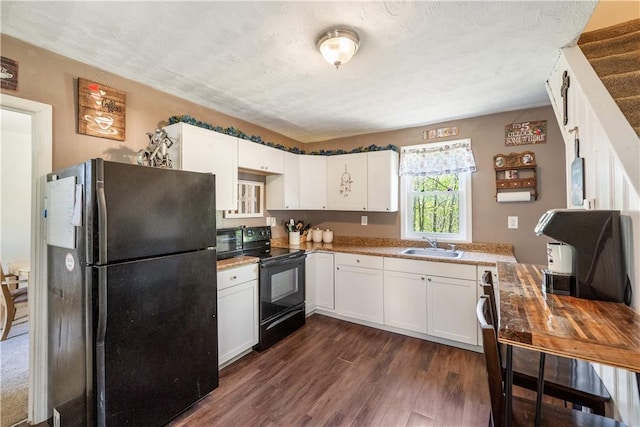 kitchen with black appliances, a sink, dark wood-style floors, white cabinetry, and light countertops