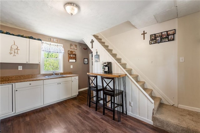 kitchen featuring a sink, dark wood-style flooring, white cabinetry, and baseboards