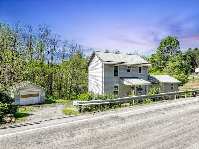 view of front of home featuring an outbuilding, metal roof, a garage, and dirt driveway