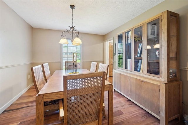 dining room featuring wood finished floors, a chandelier, and baseboards