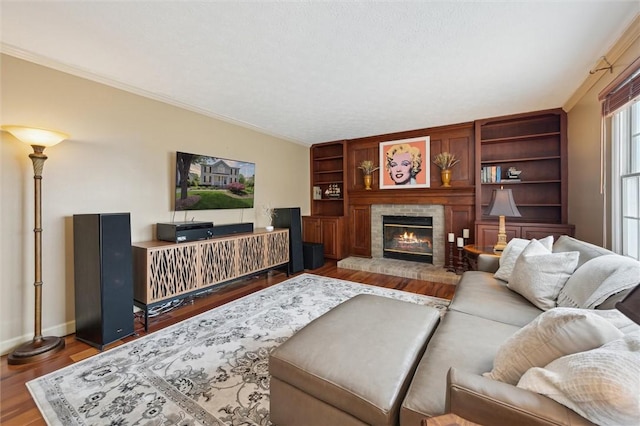 living area with ornamental molding, wood finished floors, a brick fireplace, and baseboards