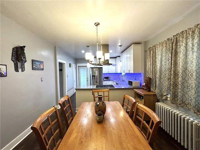 dining area featuring radiator heating unit, a chandelier, baseboards, and dark wood-style floors